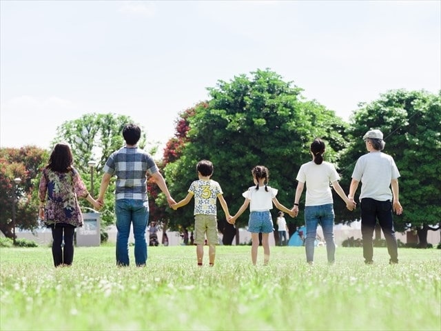 公園で手を繋ぐ家族の後ろ姿